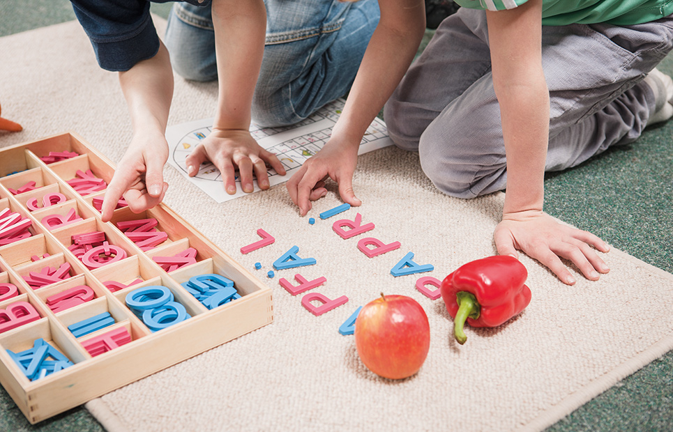 Kinder die mit Buchstaben am Boden Wörter bilden
