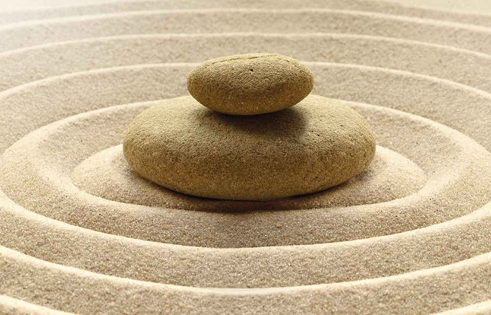 Zwei Steine aufeinander in einem Sandbett