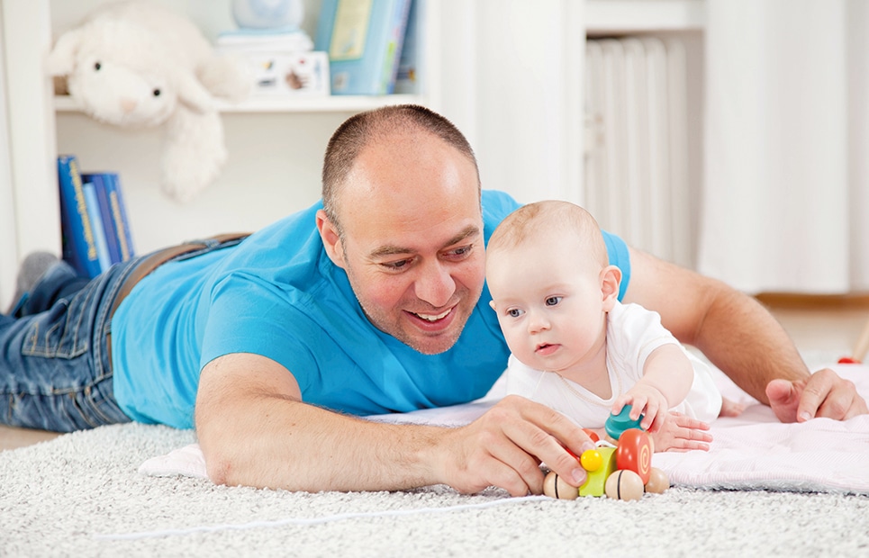 Ein Vater mit seinem Baby, spielend auf dem Fußboden auf einem Teppich