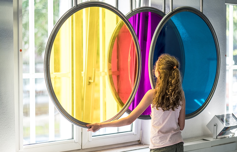 Mädchen vor drei großen Farbscheiben, die die additive Farbmischung demonstrieren
