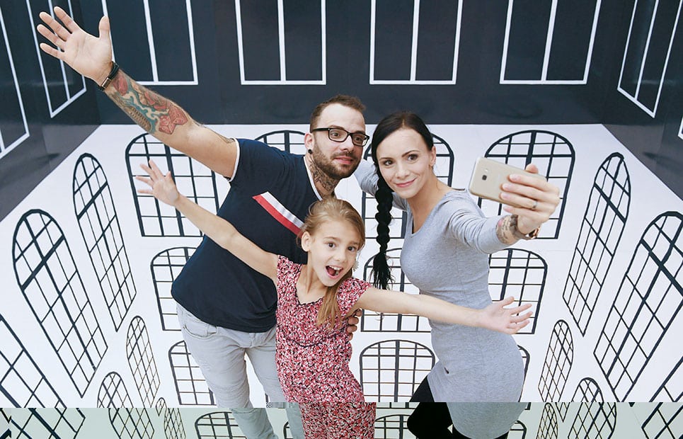 Eine dreiköpfige Familie macht ein Selfie in der Ausstellung "Vertrickst" im Kloster Eberbach